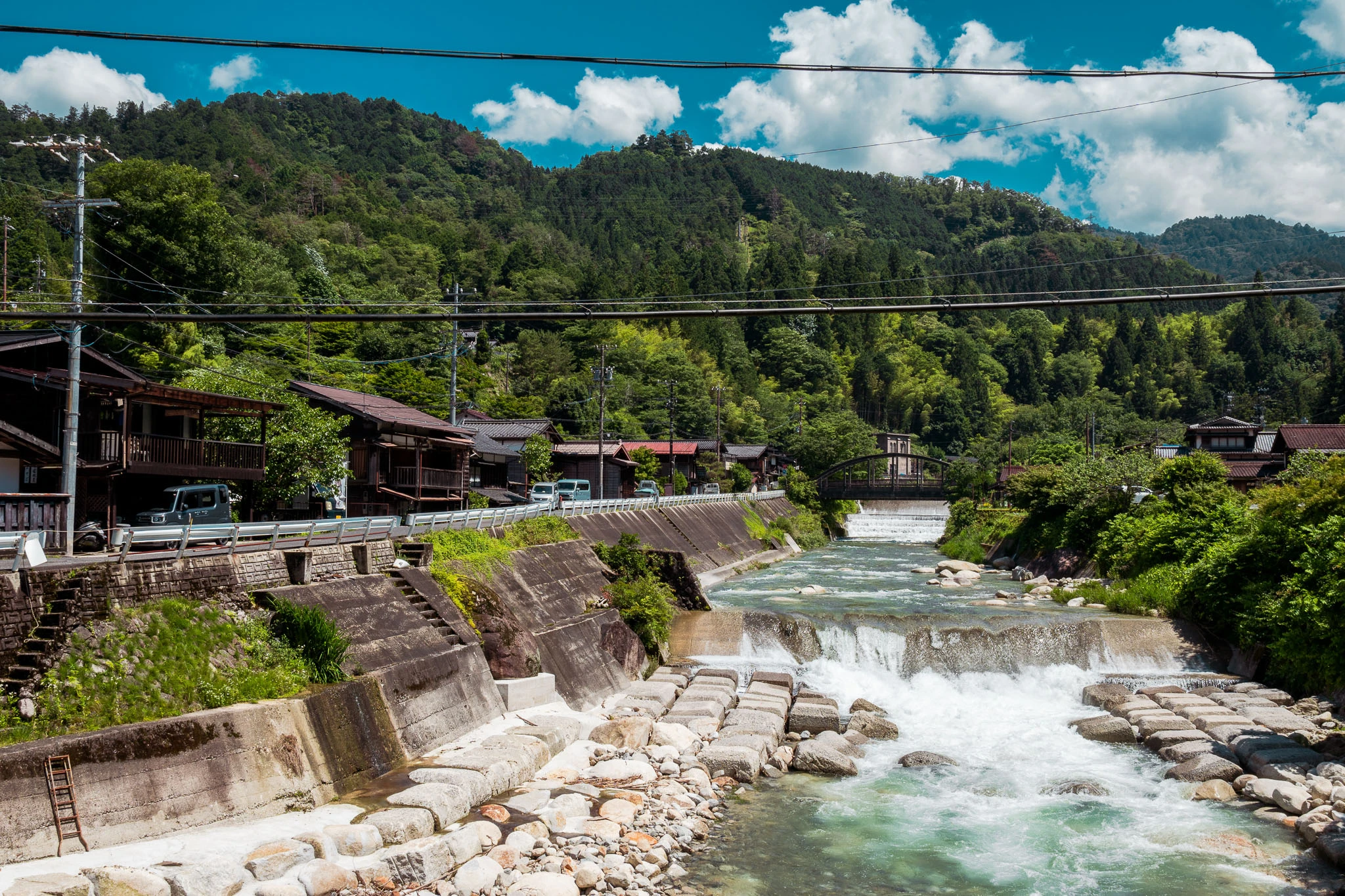 River flowing past stone embankments and wooded hills
