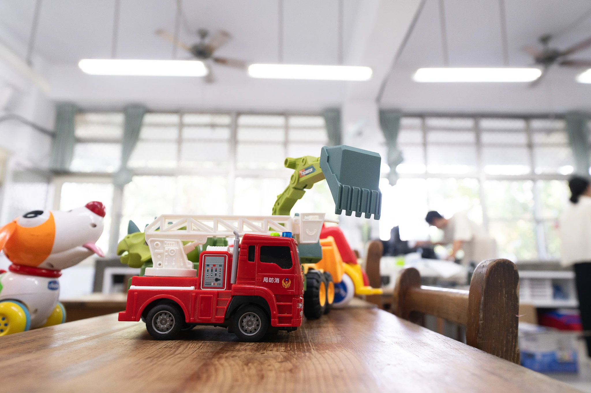 Toy vehicles on a classroom desk in daylight