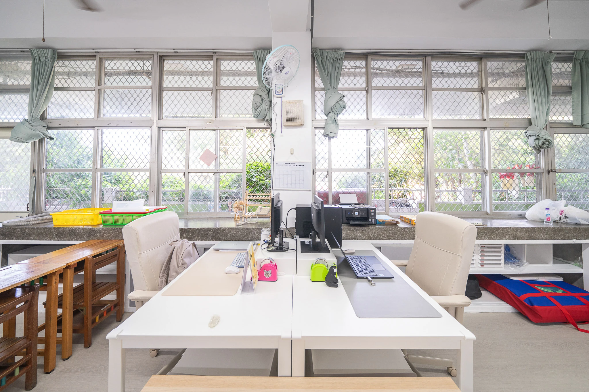 Central worktables beneath tall classroom windows