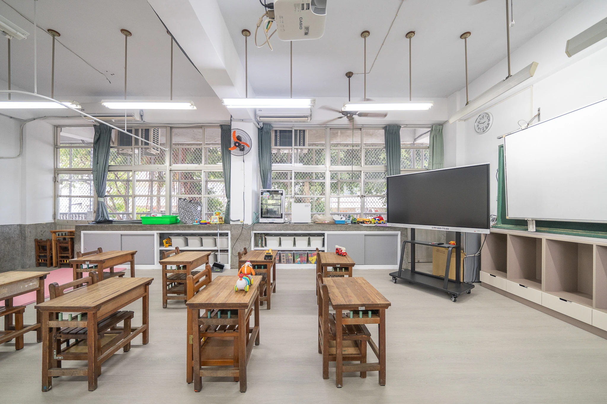 Wide view across wooden desks towards the teaching wall