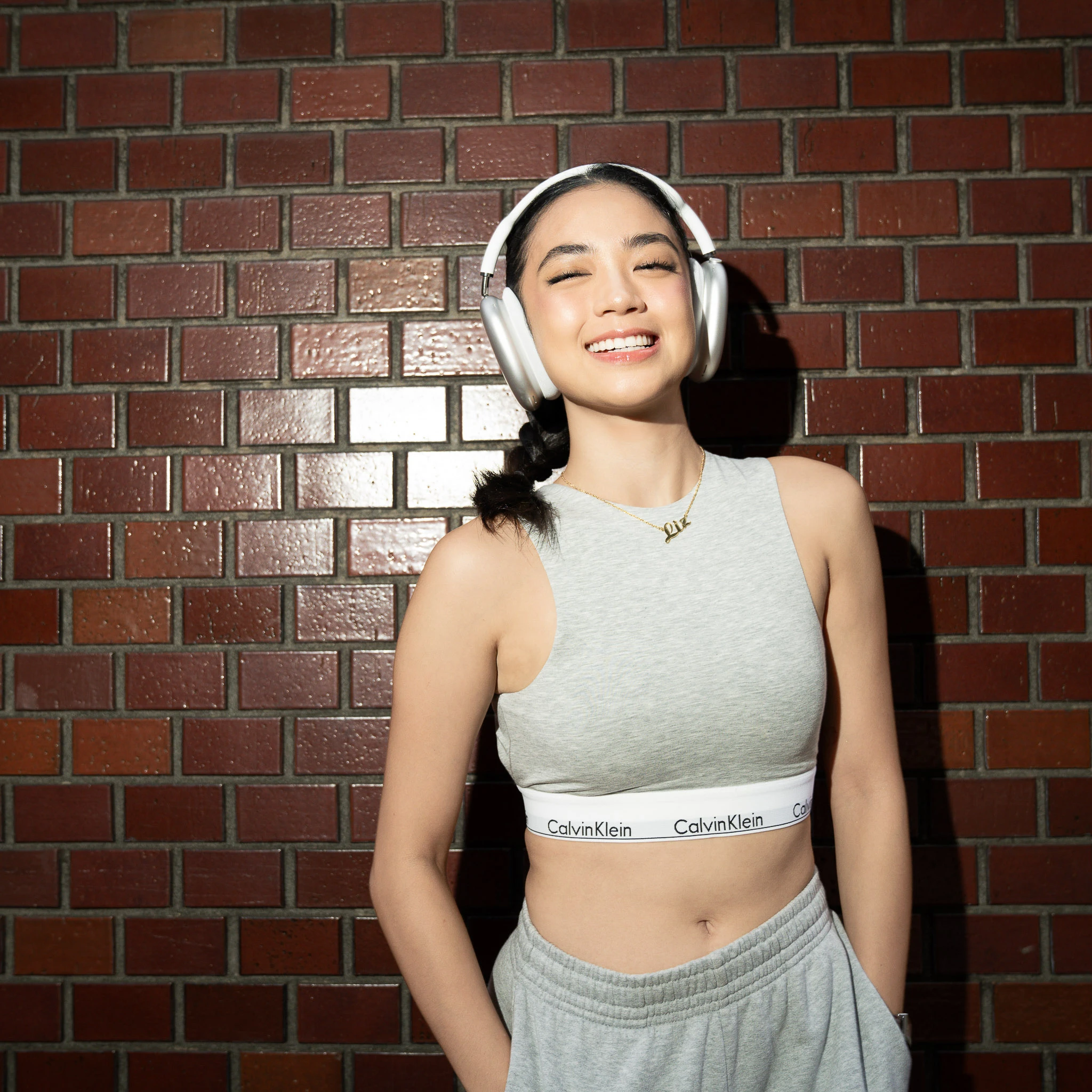 Front-facing fashion portrait against a red brick wall