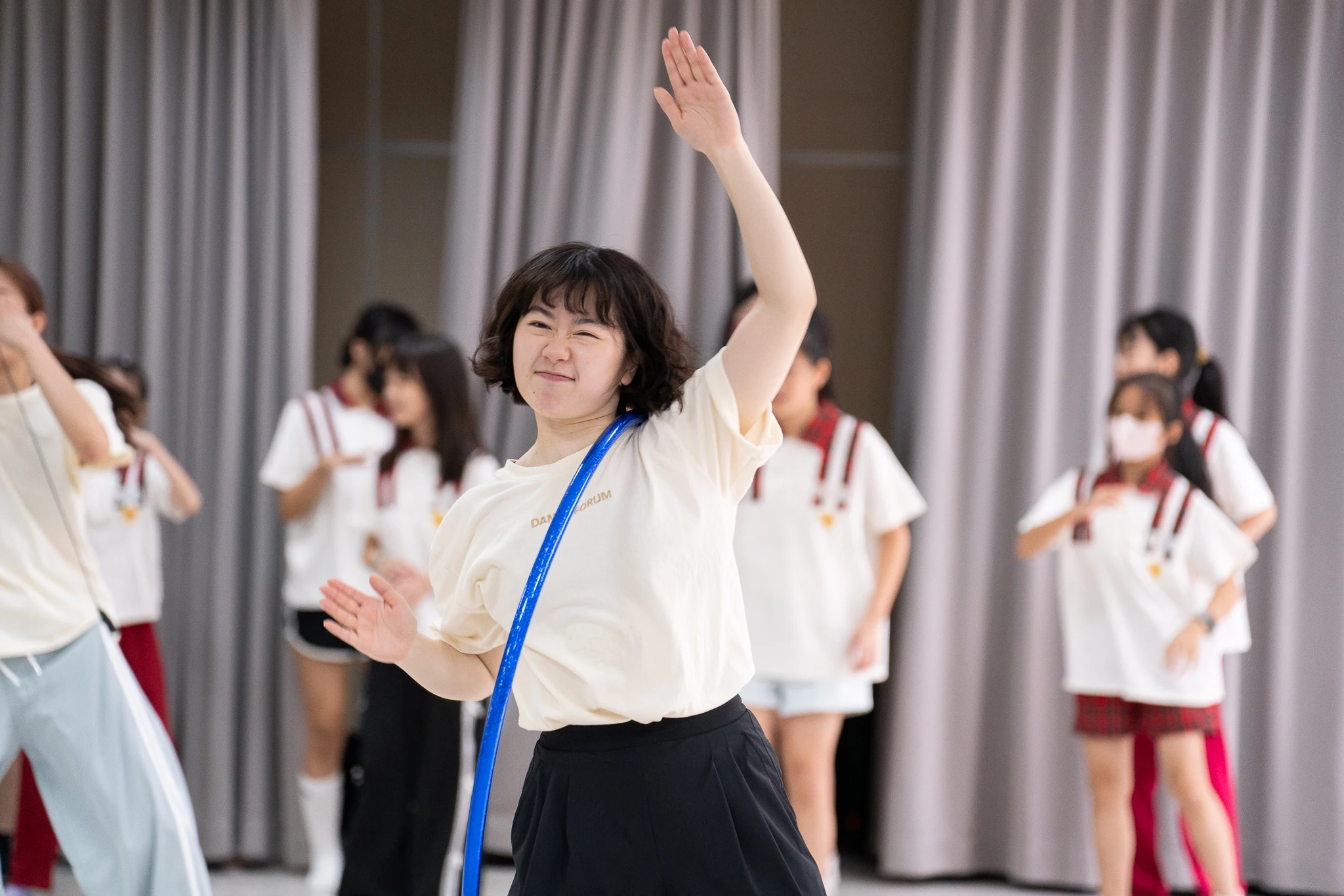Dance facilitator raising an arm while holding a blue hoop.