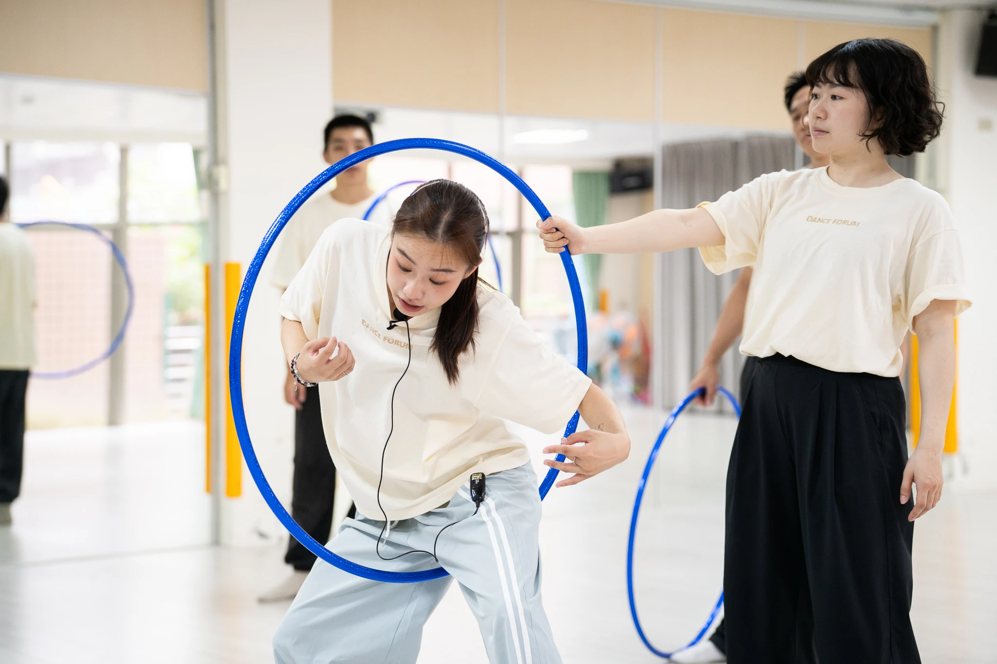 Workshop participant bending through a blue hoop held by a facilitator.