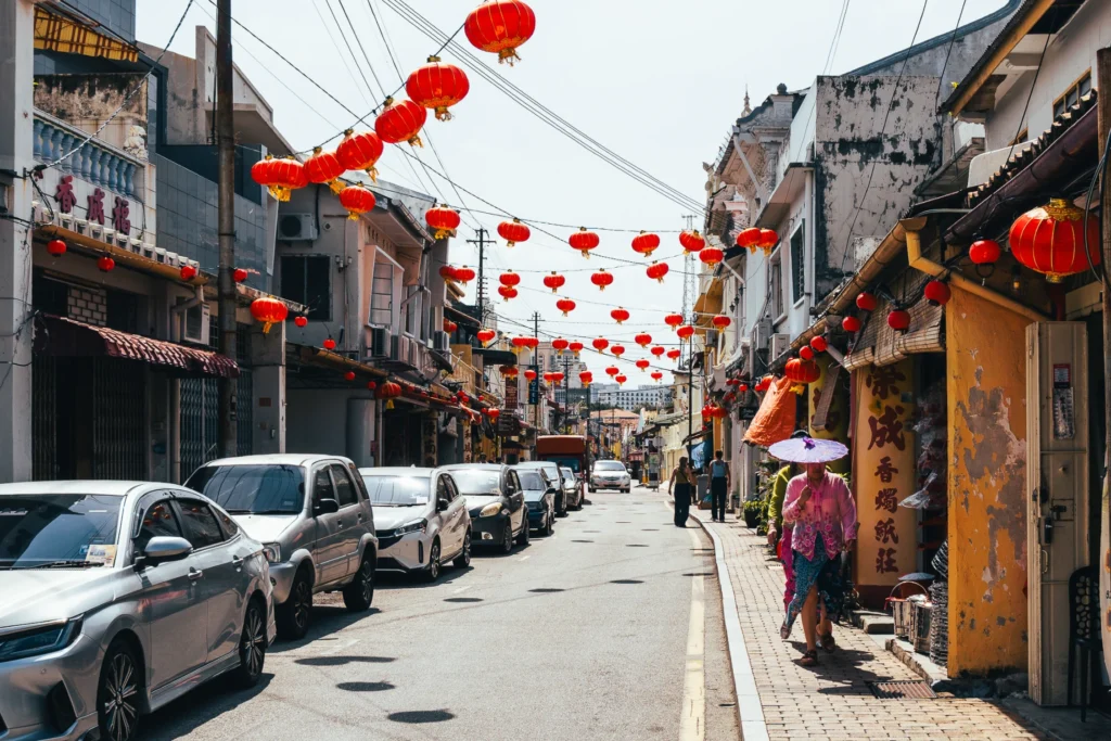 Red lanterns strung above a street lined with colourful shophouses.