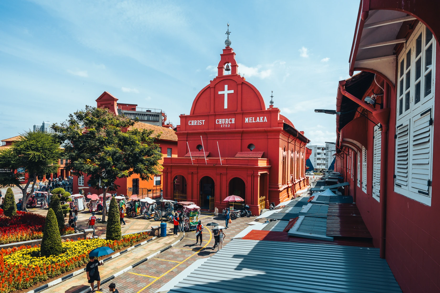 Red colonial architecture and public activity at Dutch Square in Melaka.
