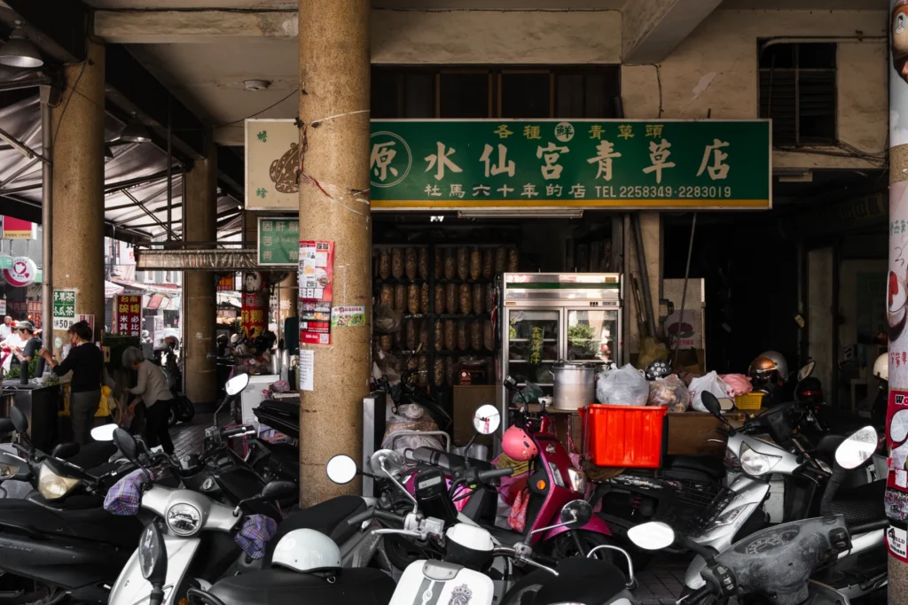 Scooters parked beneath a green Chinese shop sign.