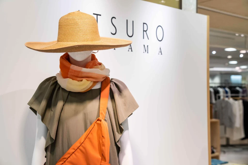 Mannequin styled with a wide-brimmed straw hat and orange accessories.