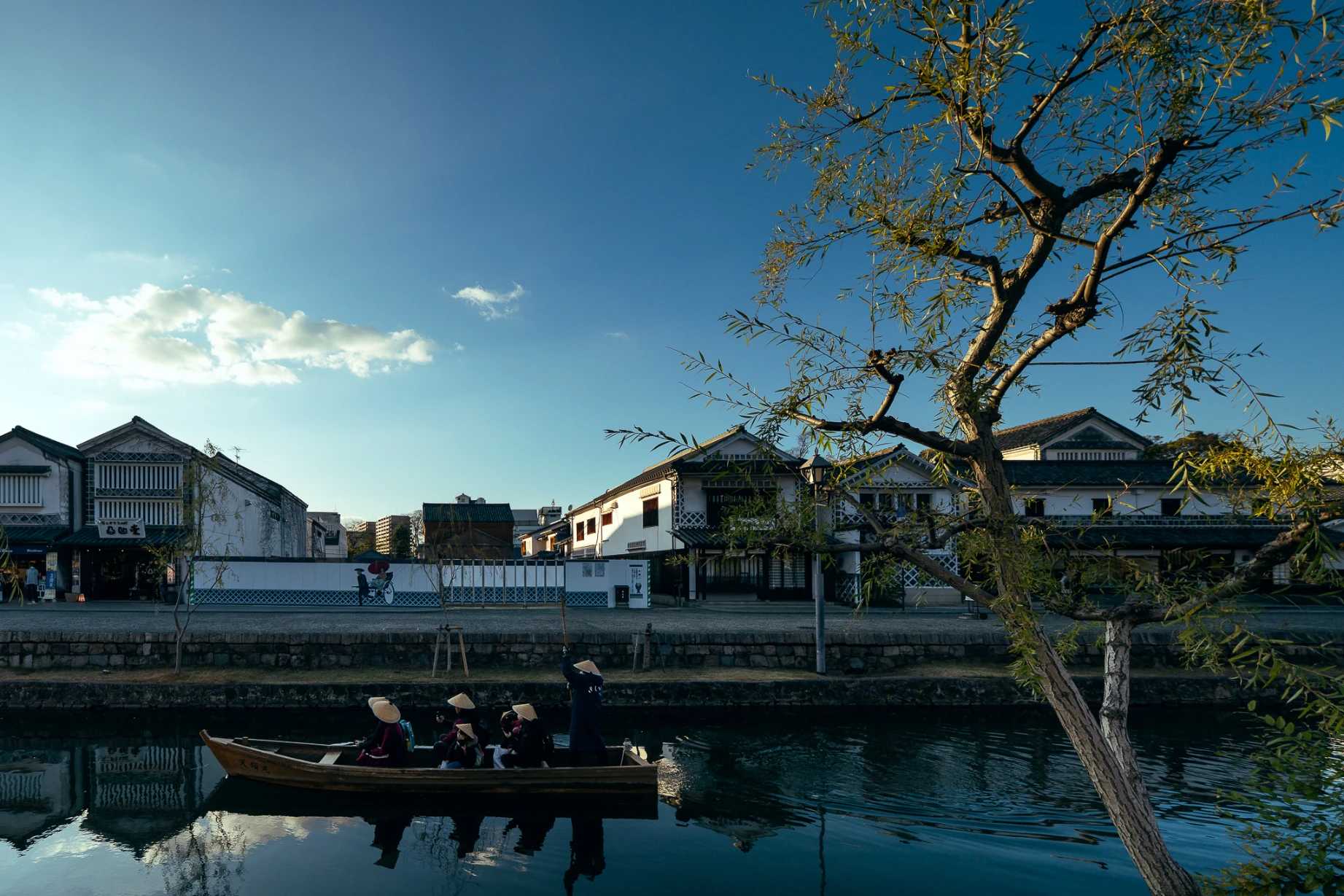 Canal and white-walled historic buildings in Kurashiki Bikan Historical Quarter.
