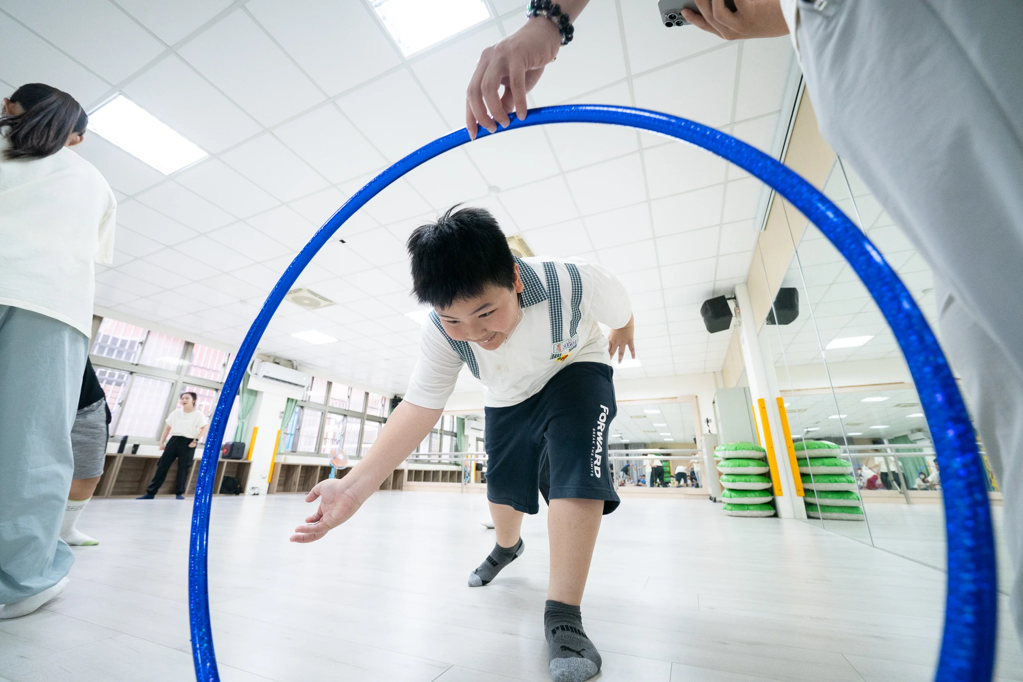 A student stepping through a blue hoop during a movement workshop.