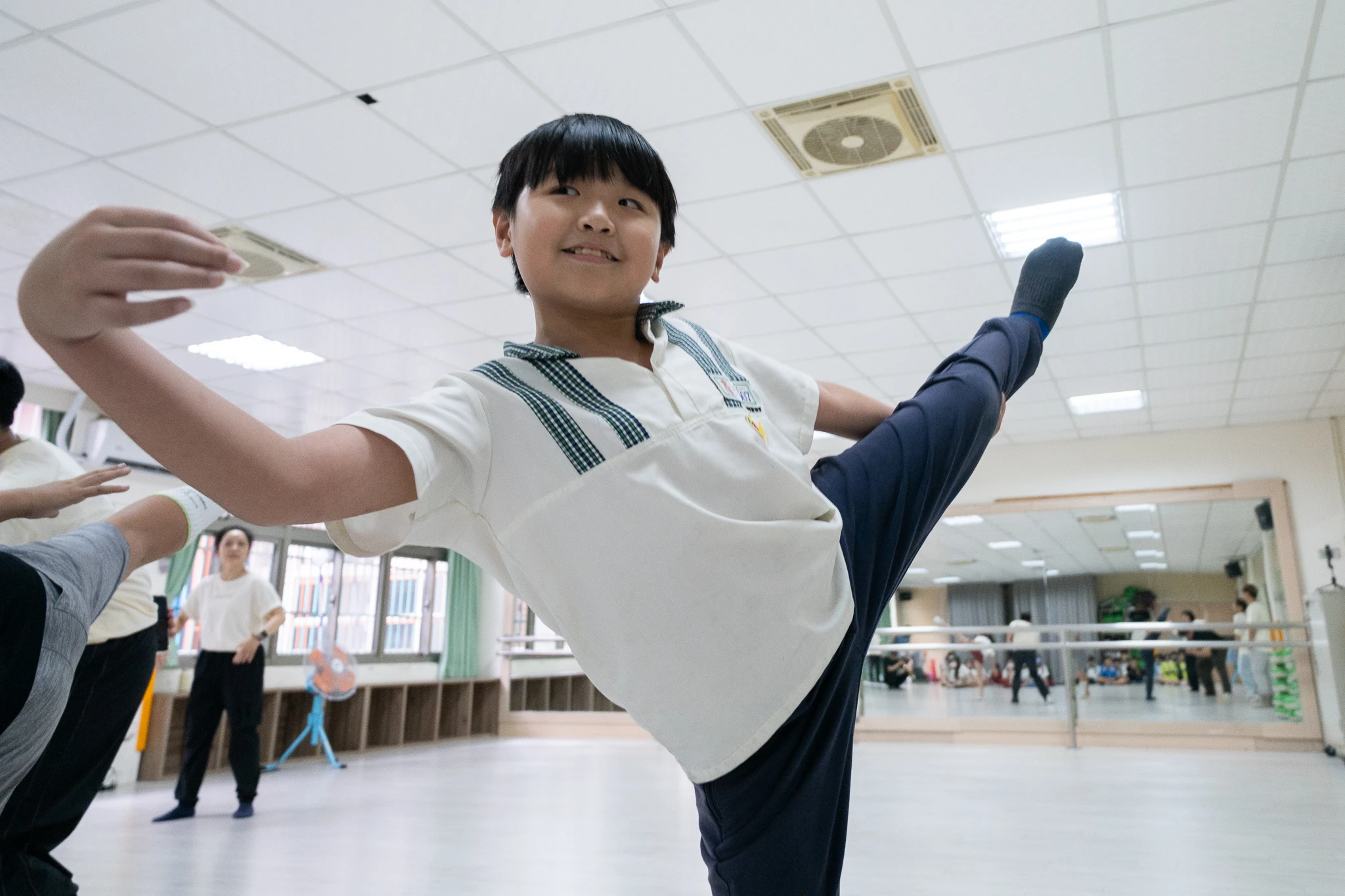 A smiling student extending one leg during a movement workshop.