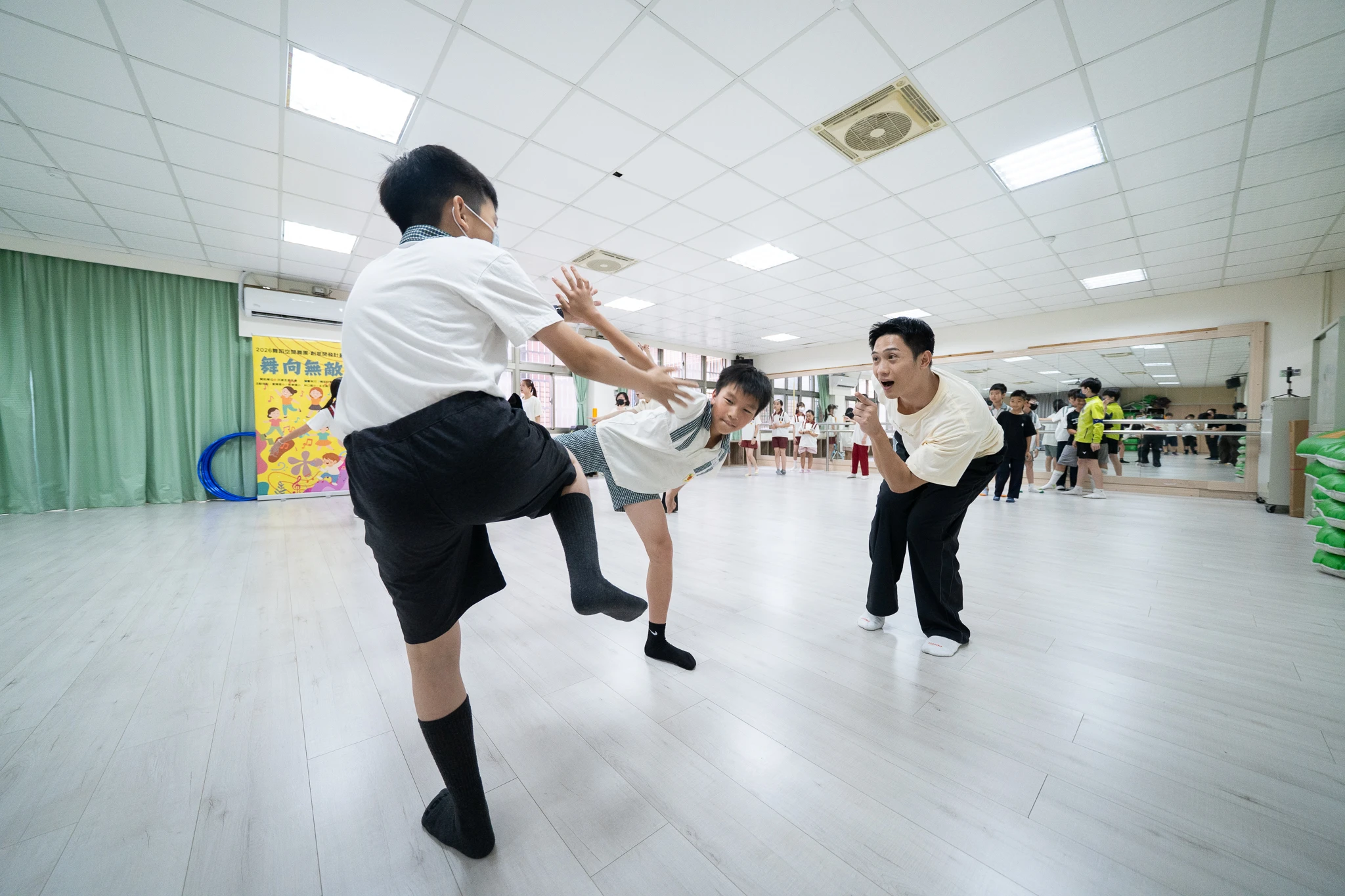 Students practising coordinated leg lifts during a movement exercise.