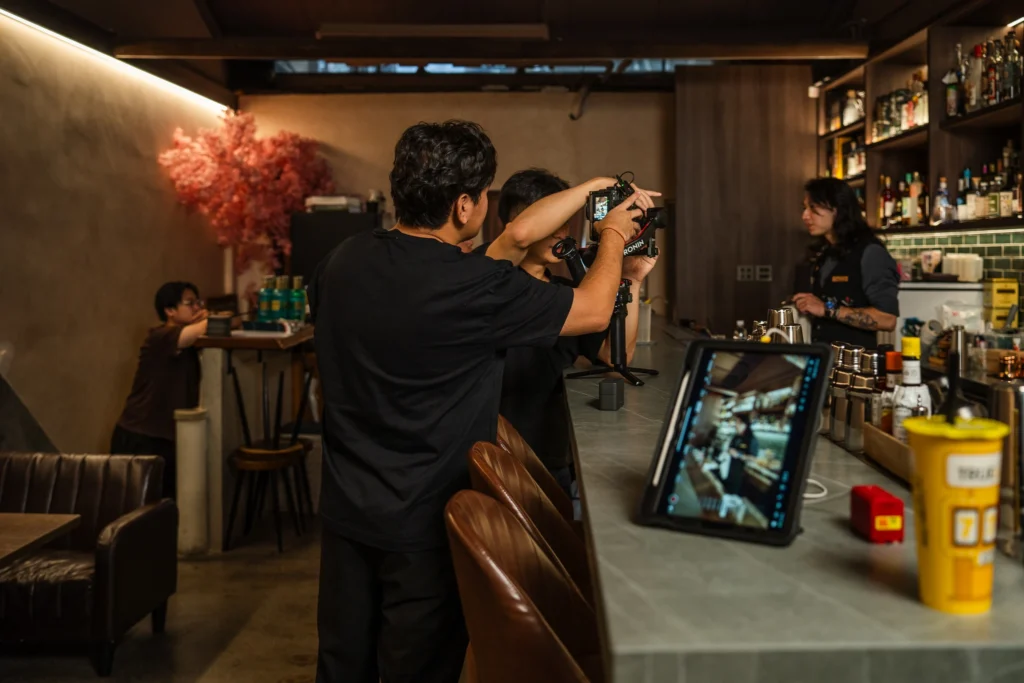 Moss & Grain crew adjusting a camera and monitoring a shoot at a bar