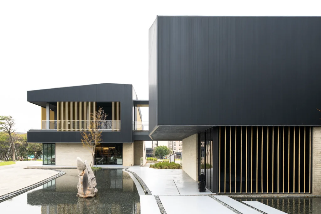 Modern museum buildings surrounding a reflecting pool and stone sculpture.