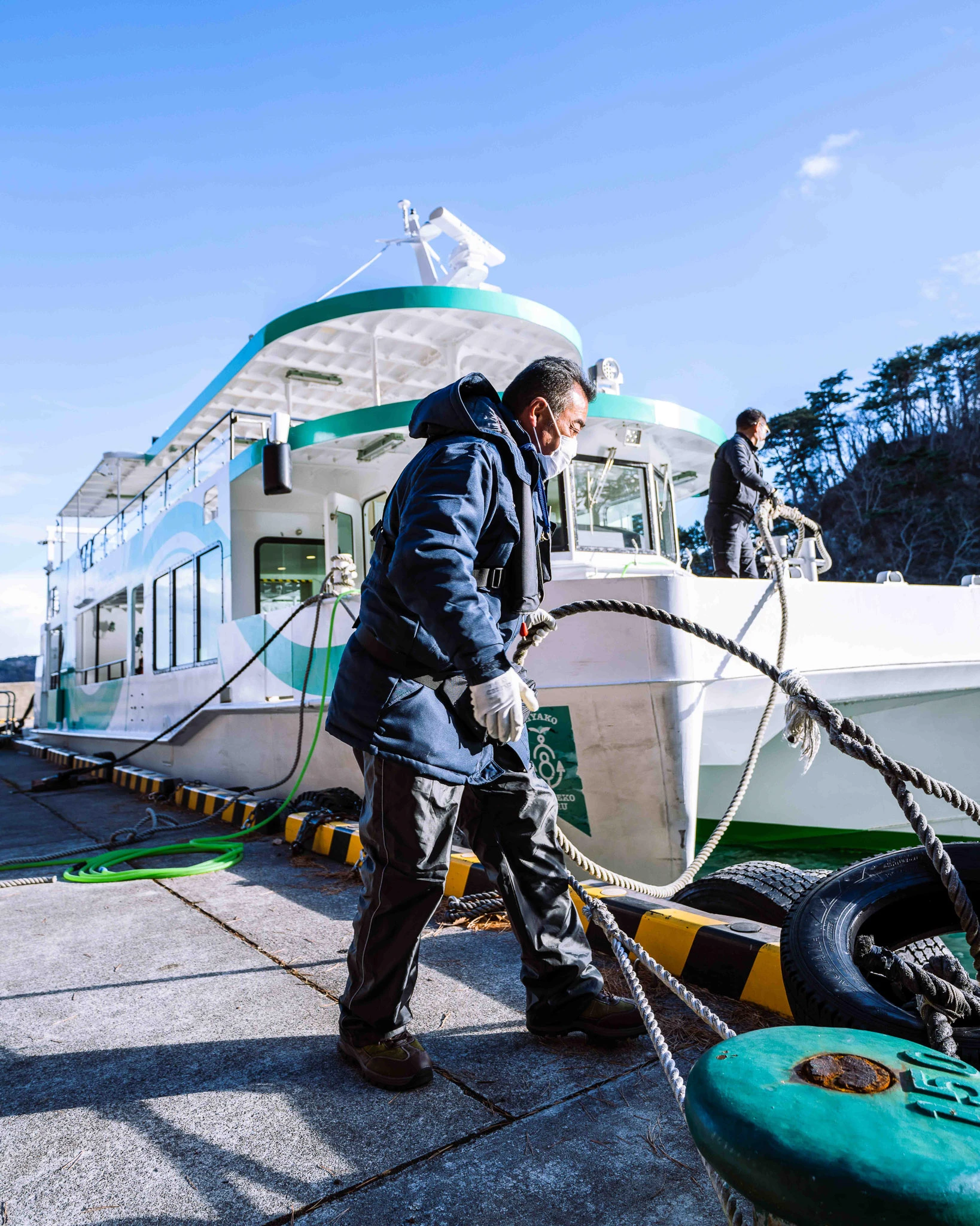 Person handling a rope beside a moored sightseeing boat