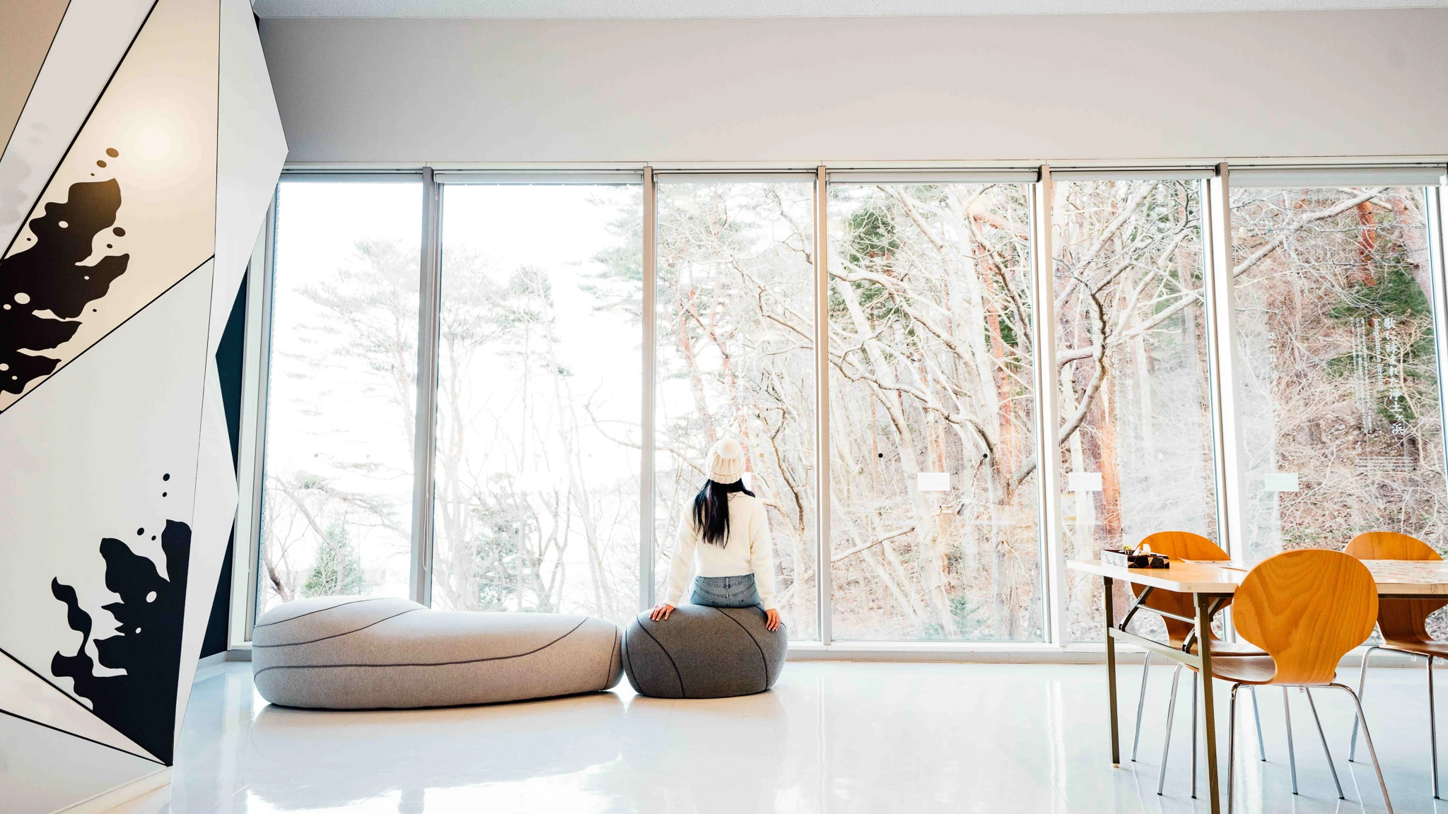 Bright seating area with a visitor beside woodland windows