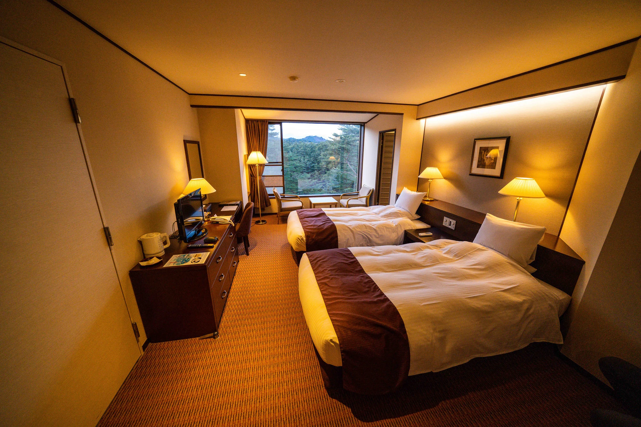 Twin beds and seating in a warmly lit guest room
