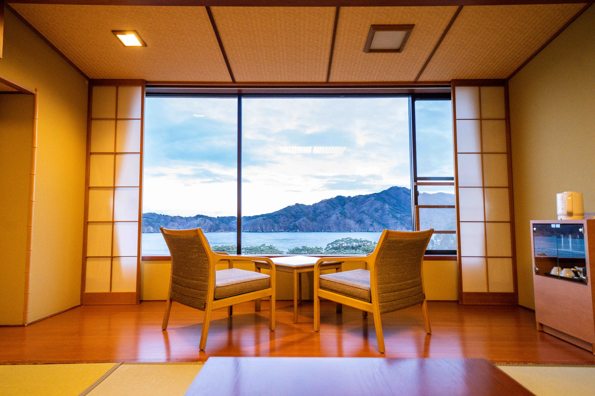 Two chairs facing the bay through shoji-framed windows