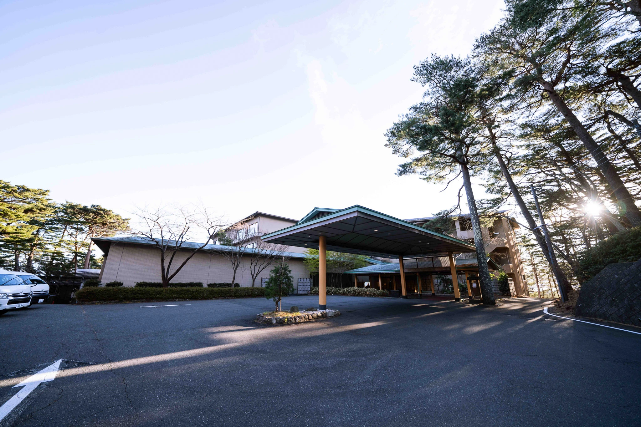 Hotel entrance sheltered by tall pine trees