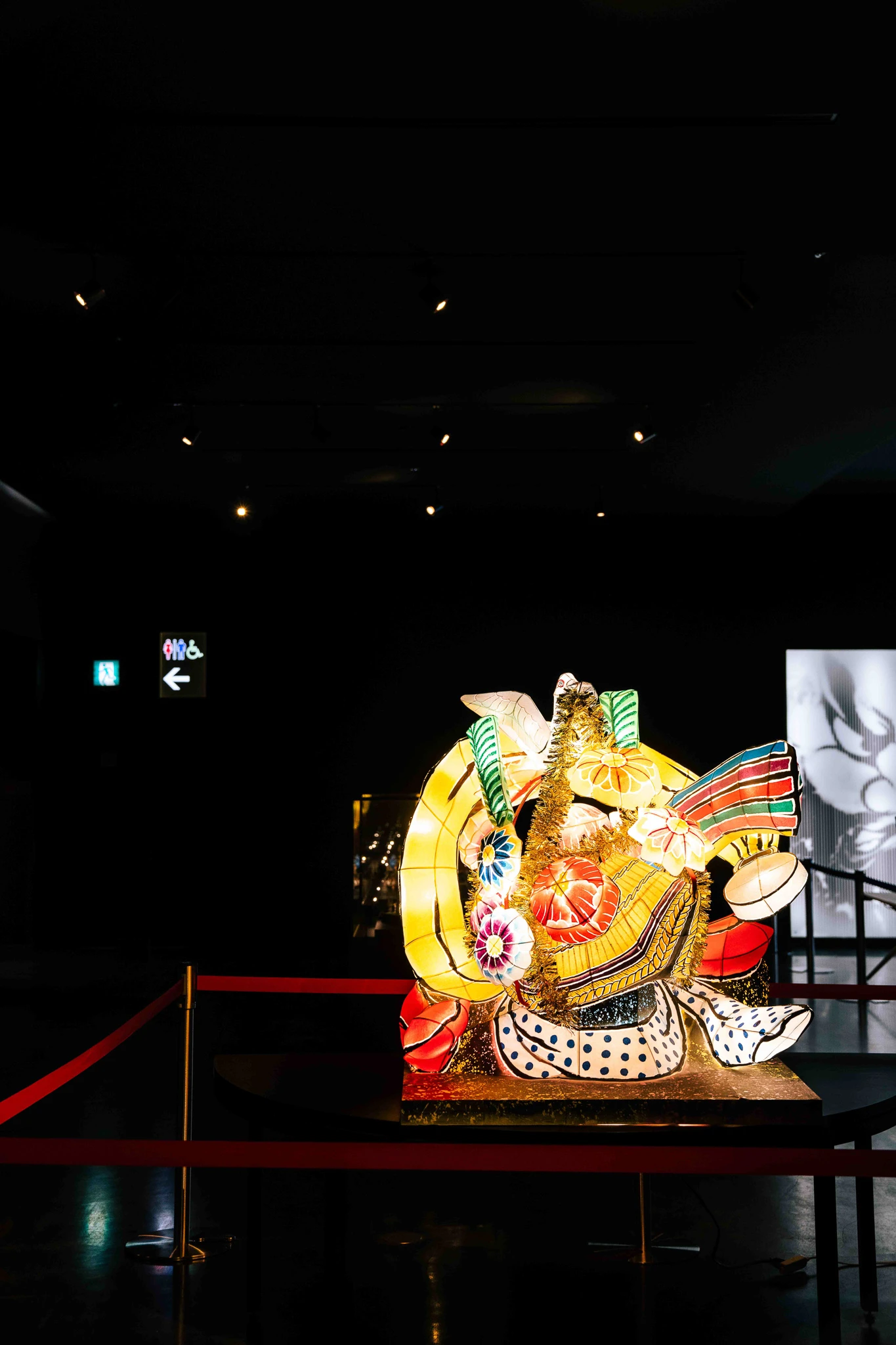 Colourful figure illuminated within a dark gallery