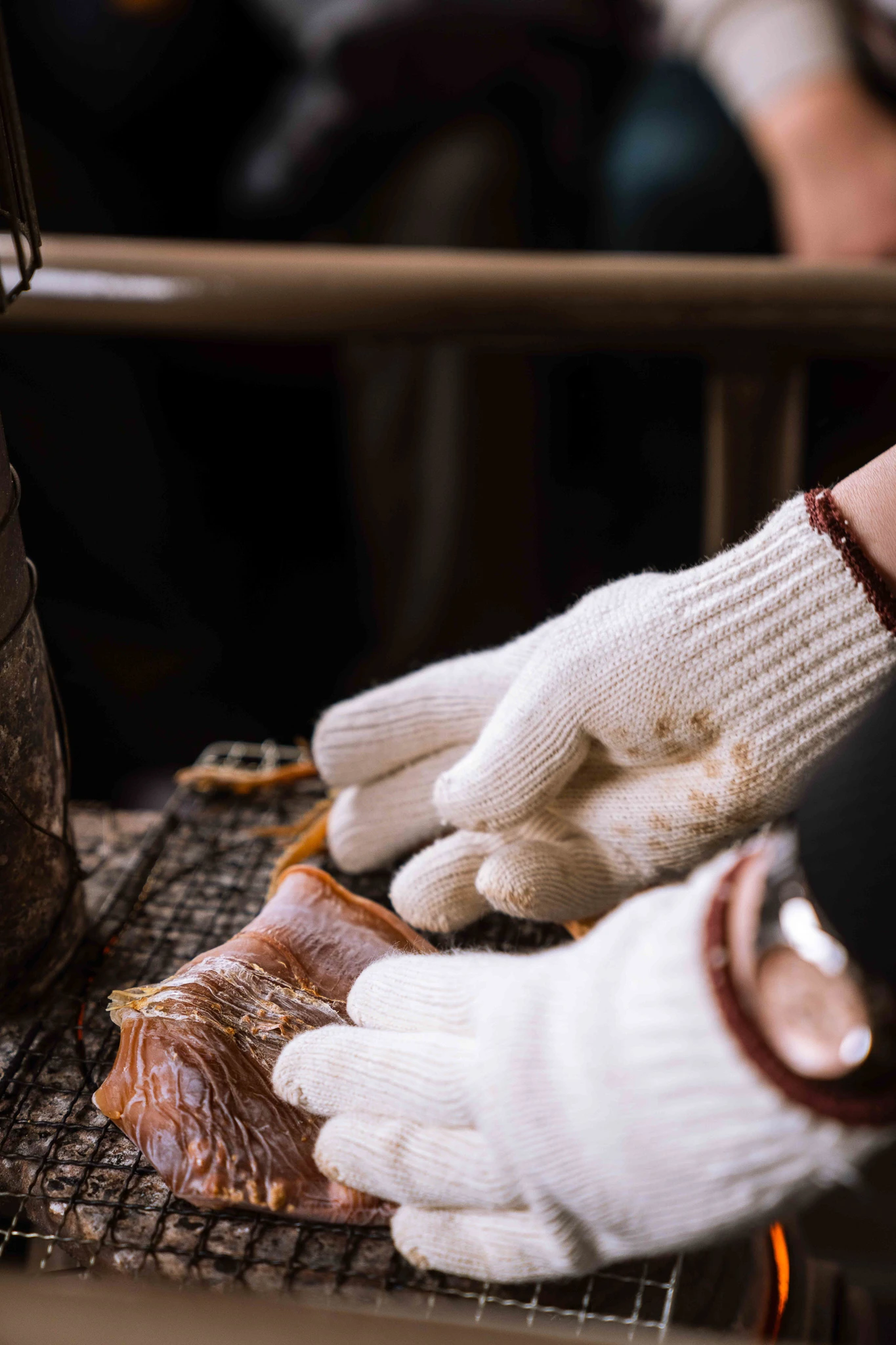 Gloved hands tending food beside the carriage stove