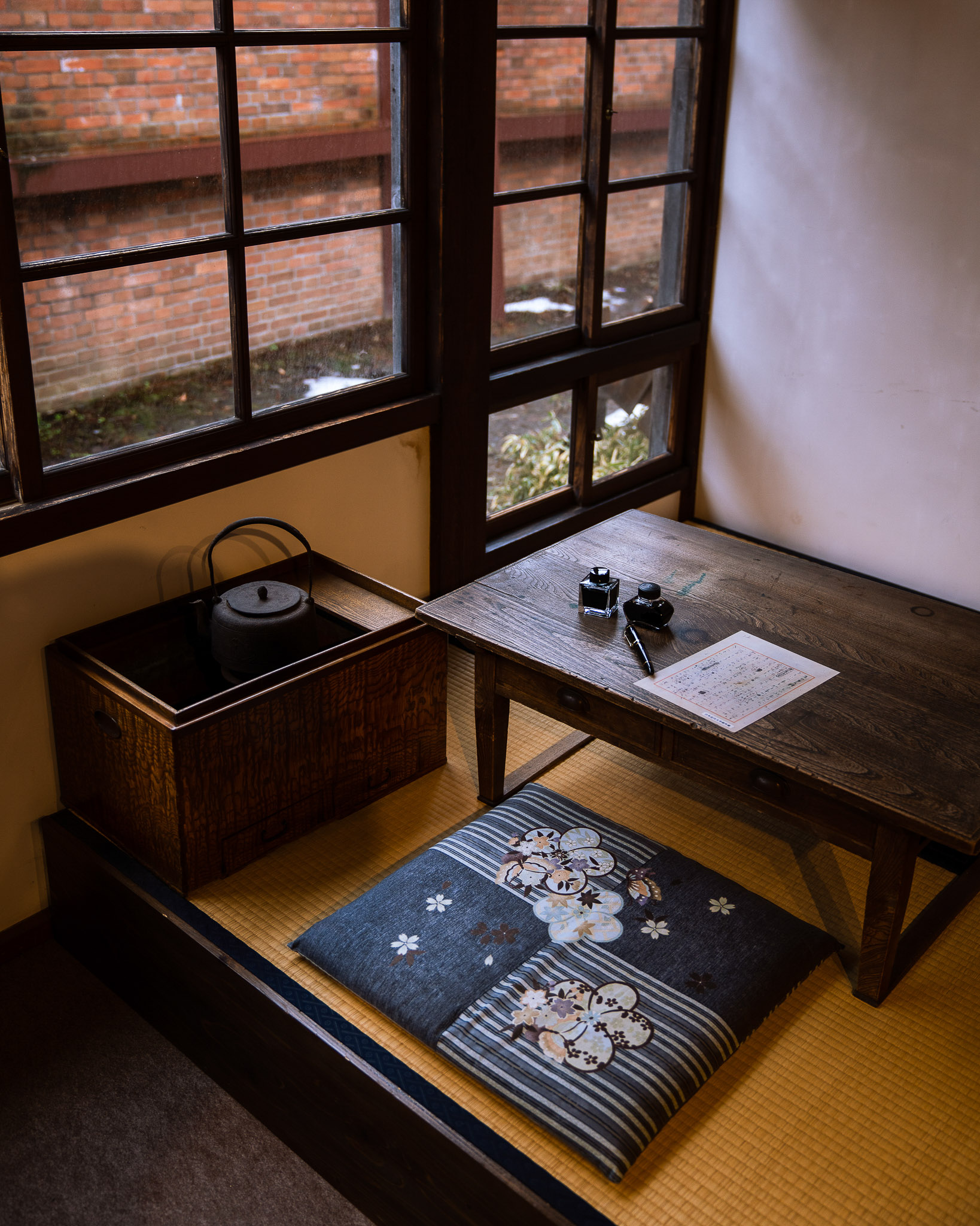 Low writing table and cushion beside a window
