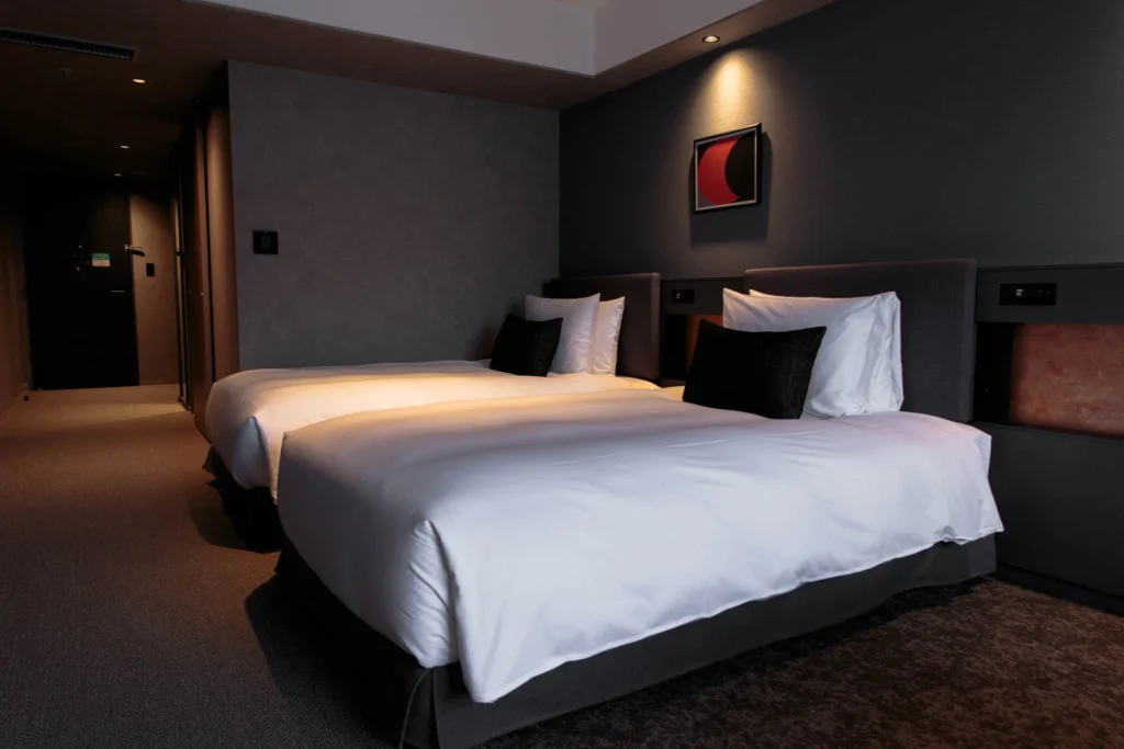 Twin beds in a softly lit room with framed artwork.