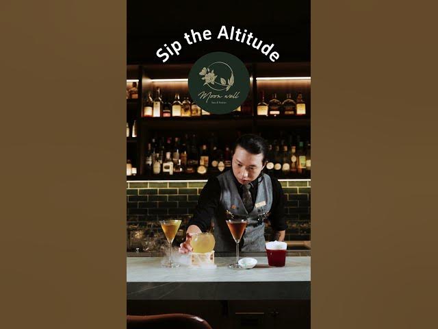 A Moonwell bartender arranging cocktails beneath the Sip the Altitude title／Sip the Altitude 字樣下整理調酒的 Moonwell 調酒師