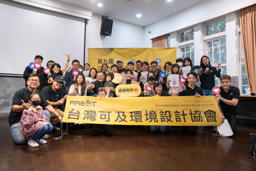 Participants holding a Taiwan accessible environment design association banner for a group photograph.